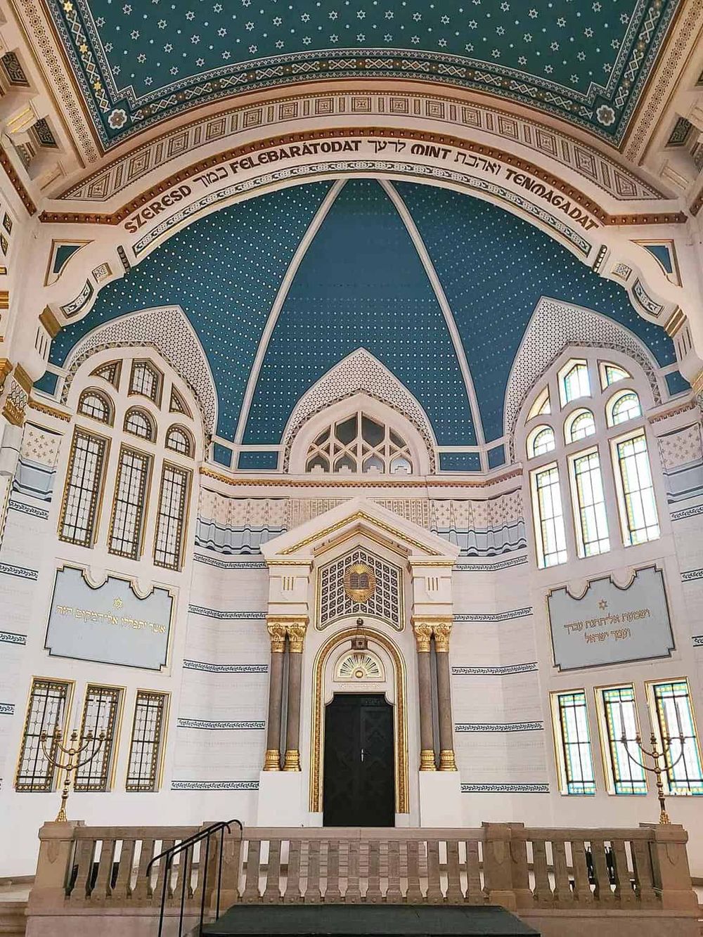 Beautiful interior of a synagogue showcasing blue and white ornate architecture, stained glass windows, and religious motifs, ideal for cultural and religious tours.
