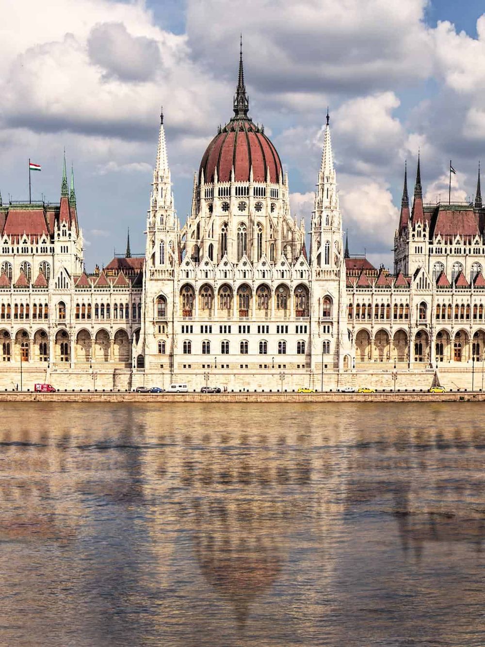 Panoramic view of the Hungarian Parliament Building in Budapest, reflecting in the Danube River, showcasing a stunning Gothic Revival architecture.
