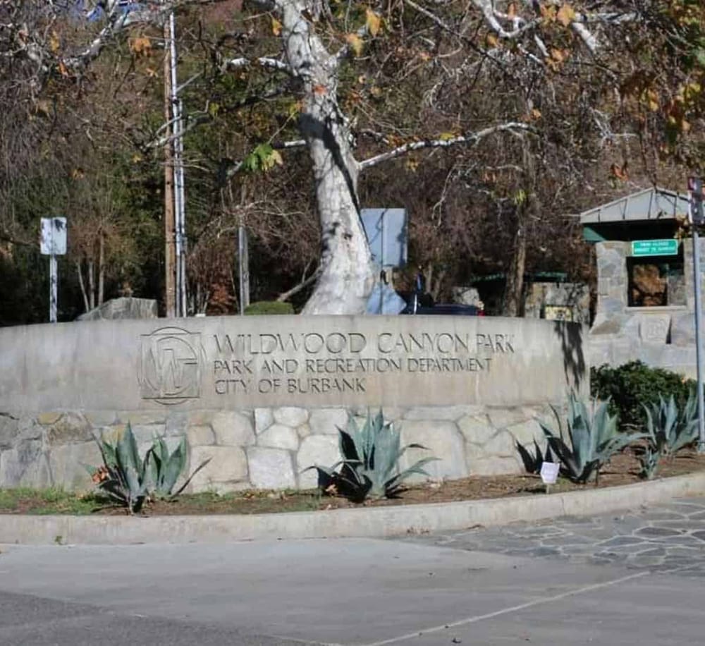 Vibrant entrance sign for Wildwood Canyon Park with desert plants and mature trees, highlighting outdoor recreation and nature in Burbank, California.