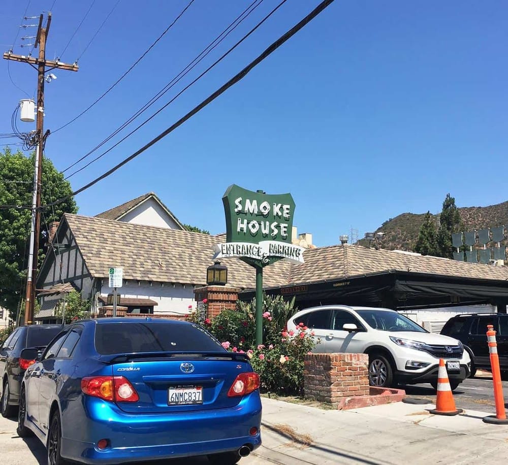 Vintage Smoke House restaurant with parking area, classic sign, and blue sky backdrop.