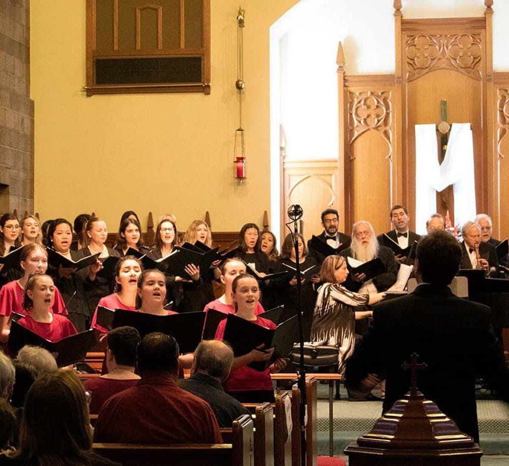 Chorus of children and adults singing in a church choir during a musical performance.