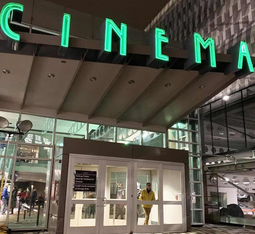 Cinemas at night with neon sign displaying "CINEMA" outside for movie entertainment.