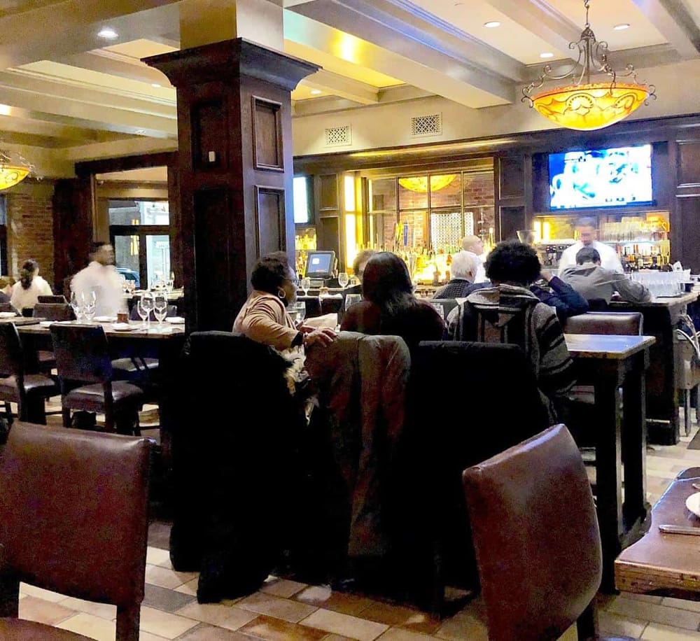 Elegant bar and restaurant interior with customers enjoying drinks and conversations, perfect for dining out or social gatherings.