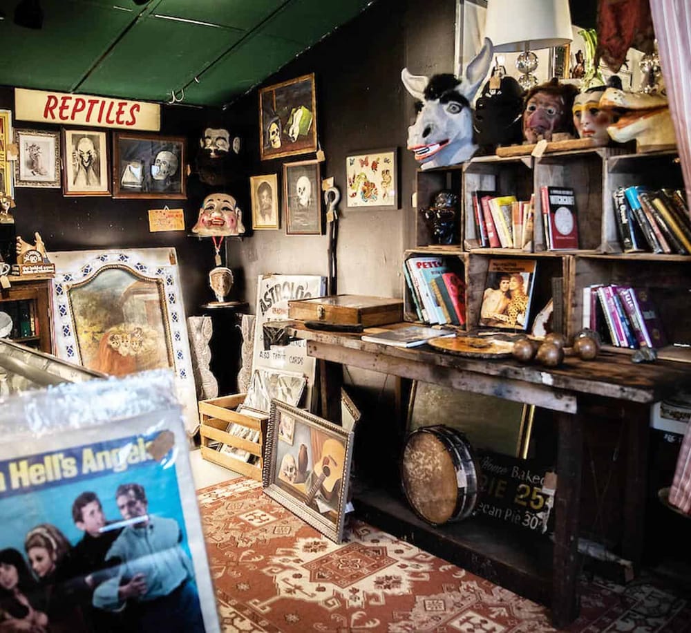 Antique shop with masks, vintage books, and eclectic decor for unique collectibles.