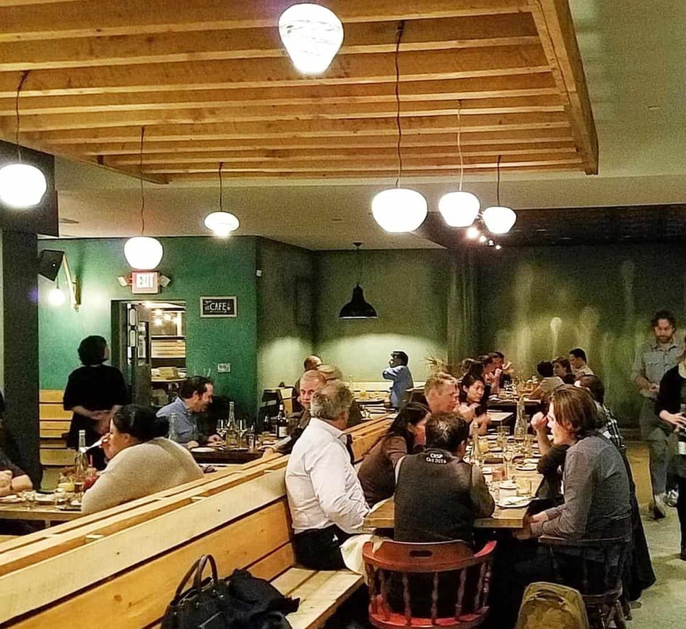 Cozy restaurant interior with diners enjoying meals, modern lighting, and welcoming atmosphere.