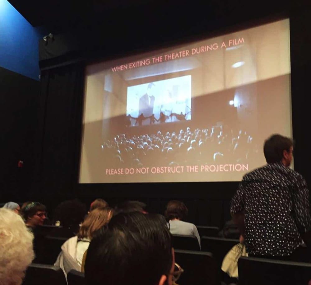 1. Projection screen in movie theater with viewers watching a film.