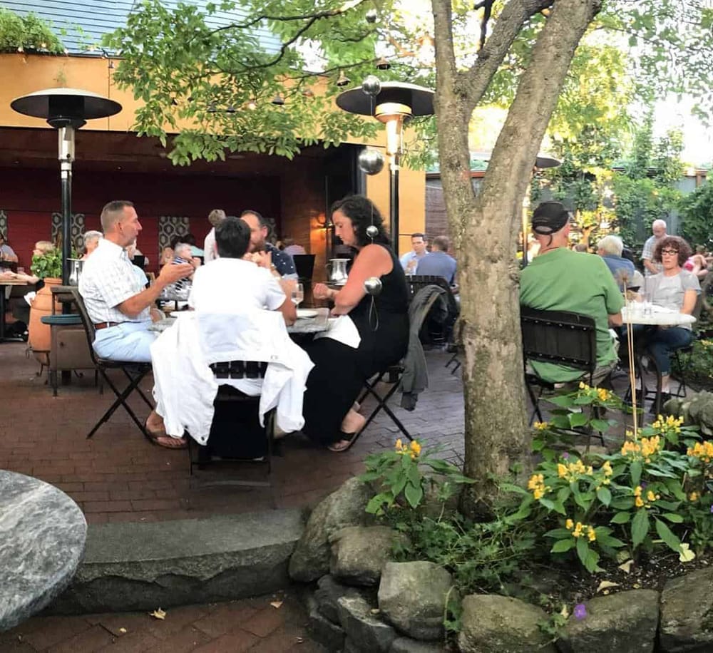 Enjoying outdoor dining at QuestForDirections restaurant with surrounded greenery and a warm patio setting.
