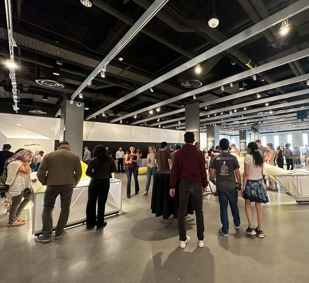 Brightly lit modern conference hall with diverse attendees engaging with exhibits and displays.