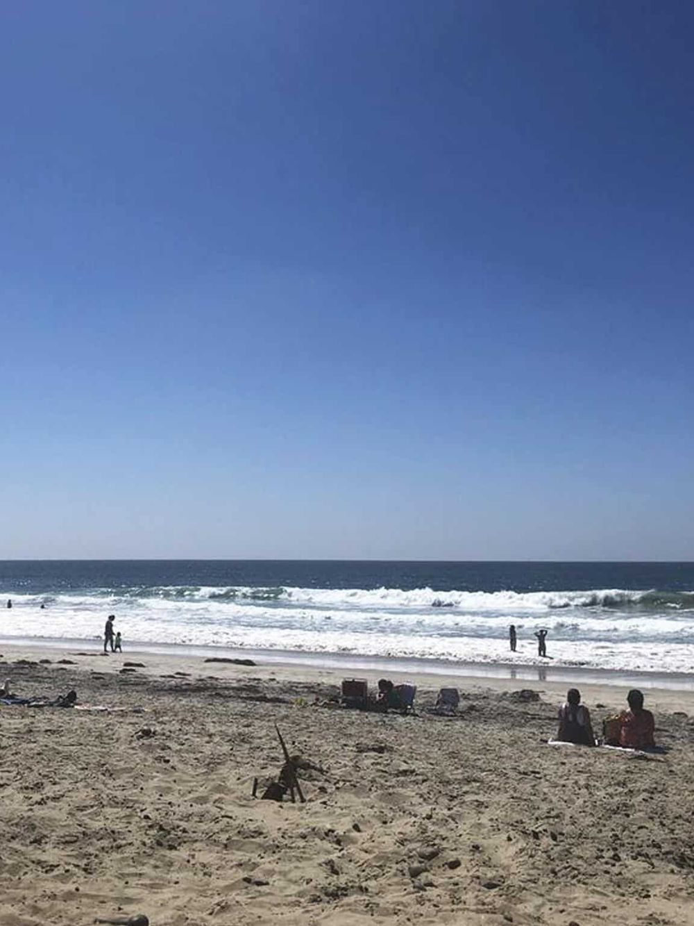 Relaxing beach scene with people enjoying sunny day at the ocean.