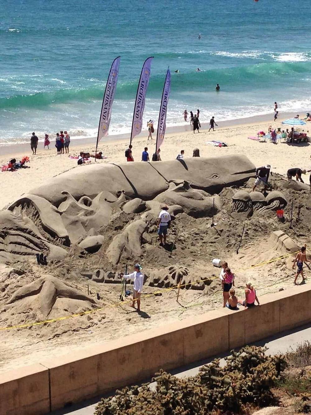Elegant sand sculpture of a whale at the beach, attracting tourists and art enthusiasts.