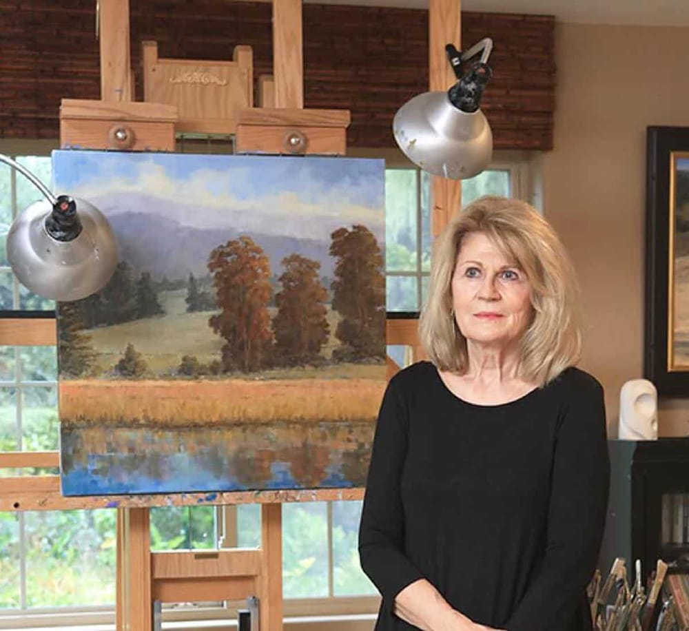 Colorful landscape painting of trees with an elderly woman artist in her studio.