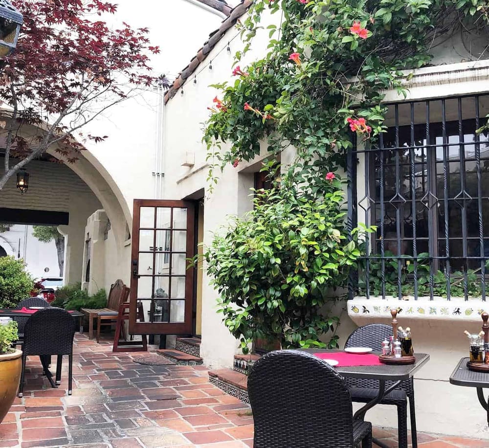 Outdoor patio with lush greenery and flowering plants, perfect for dining and relaxation.