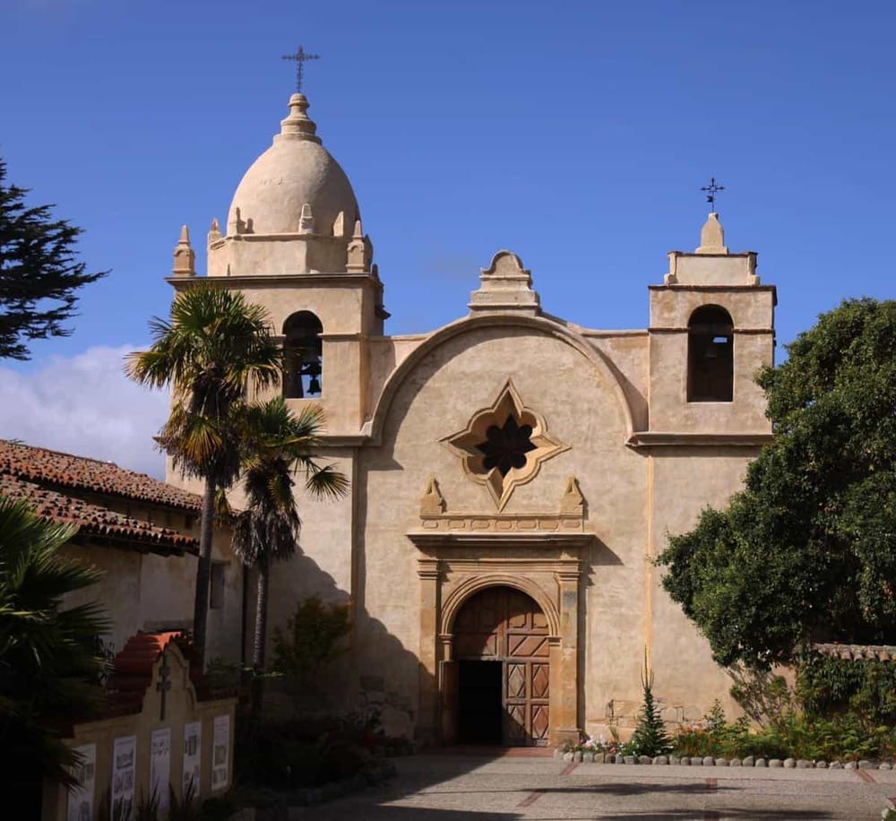 Historic mission-style church with stucco facade and twin bell towers in sunny California.