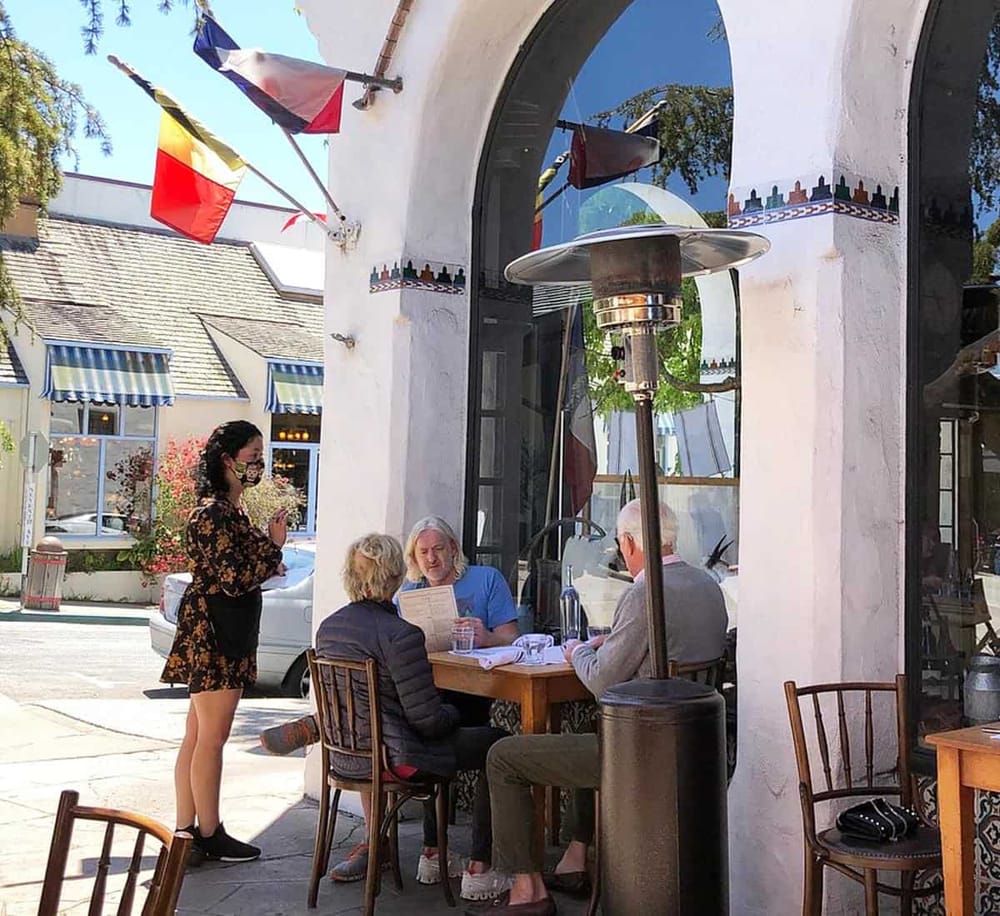 1. Outdoor dining at a restaurant with American flags and patio heaters on a sunny day.