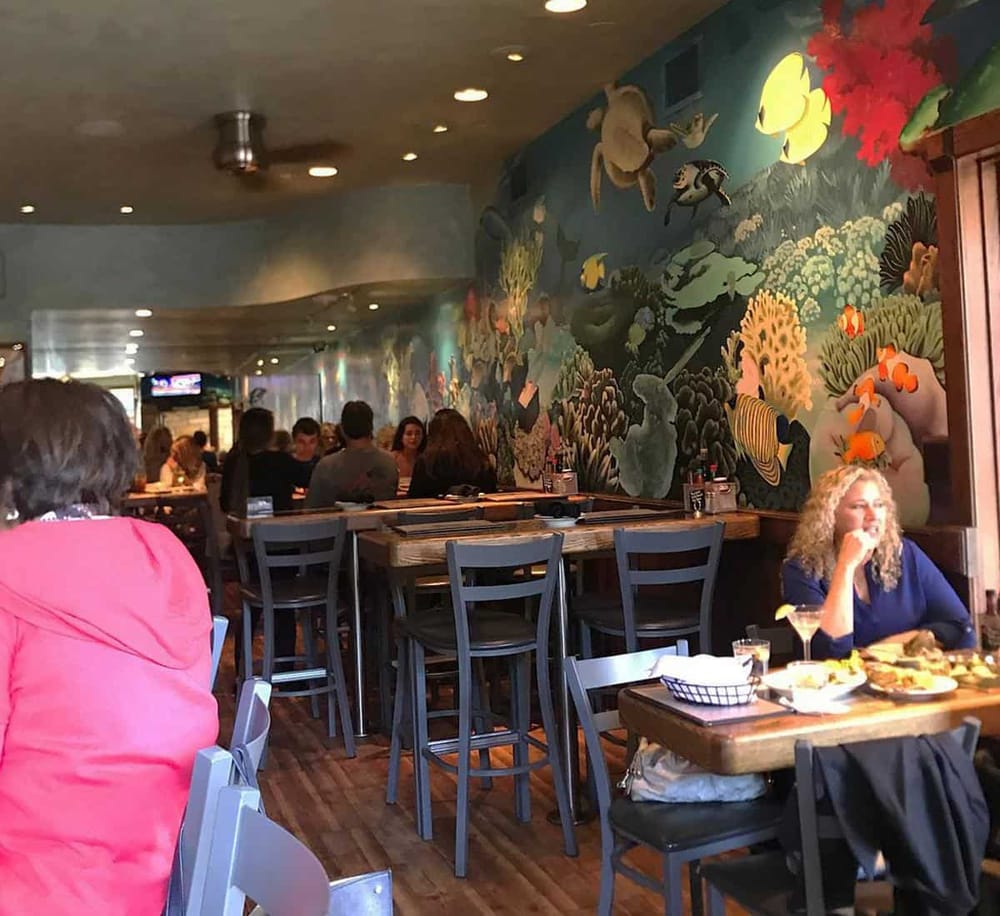 Vibrant underwater-themed restaurant mural with diners enjoying seafood and cocktails.