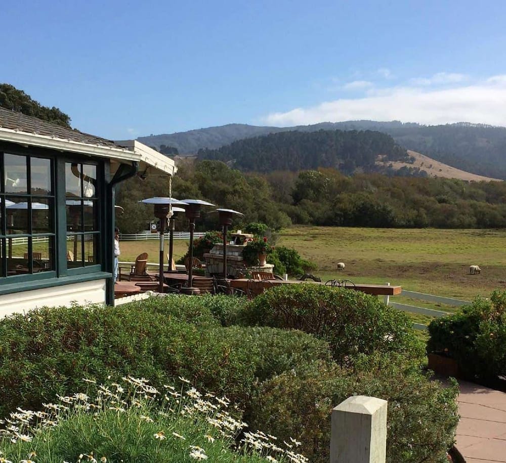 Serene outdoor patio with scenic mountain views, lush greenery, and cozy seating in a peaceful countryside setting.