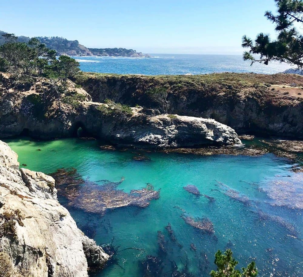 Serene coastal landscape with turquoise water, rocky cliffs, and lush trees, perfect for nature exploration and ocean adventures.