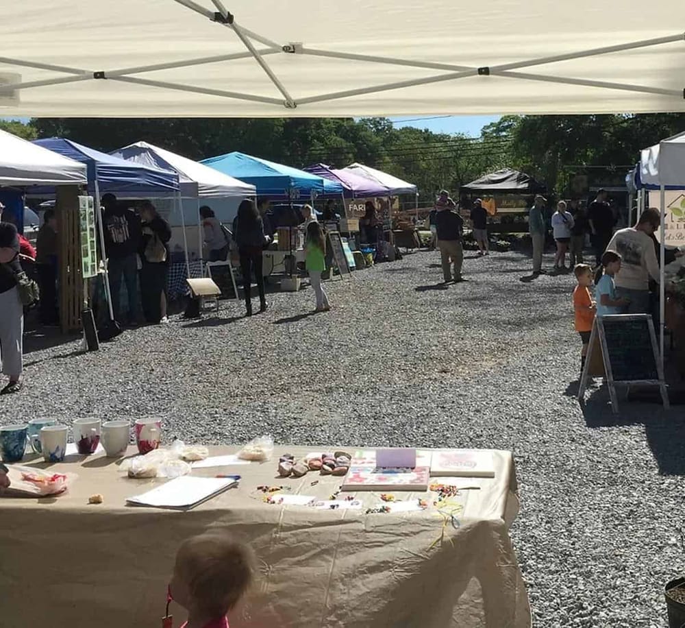 Colorful outdoor farmer's market with various vendor tents and shoppers.
