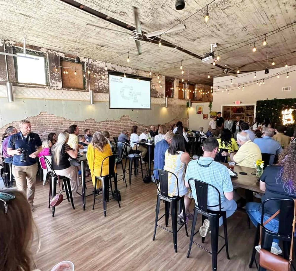 Modern restaurant interior with exposed brick walls, string lights, and a large screen for presentations, ideal for events and gatherings.