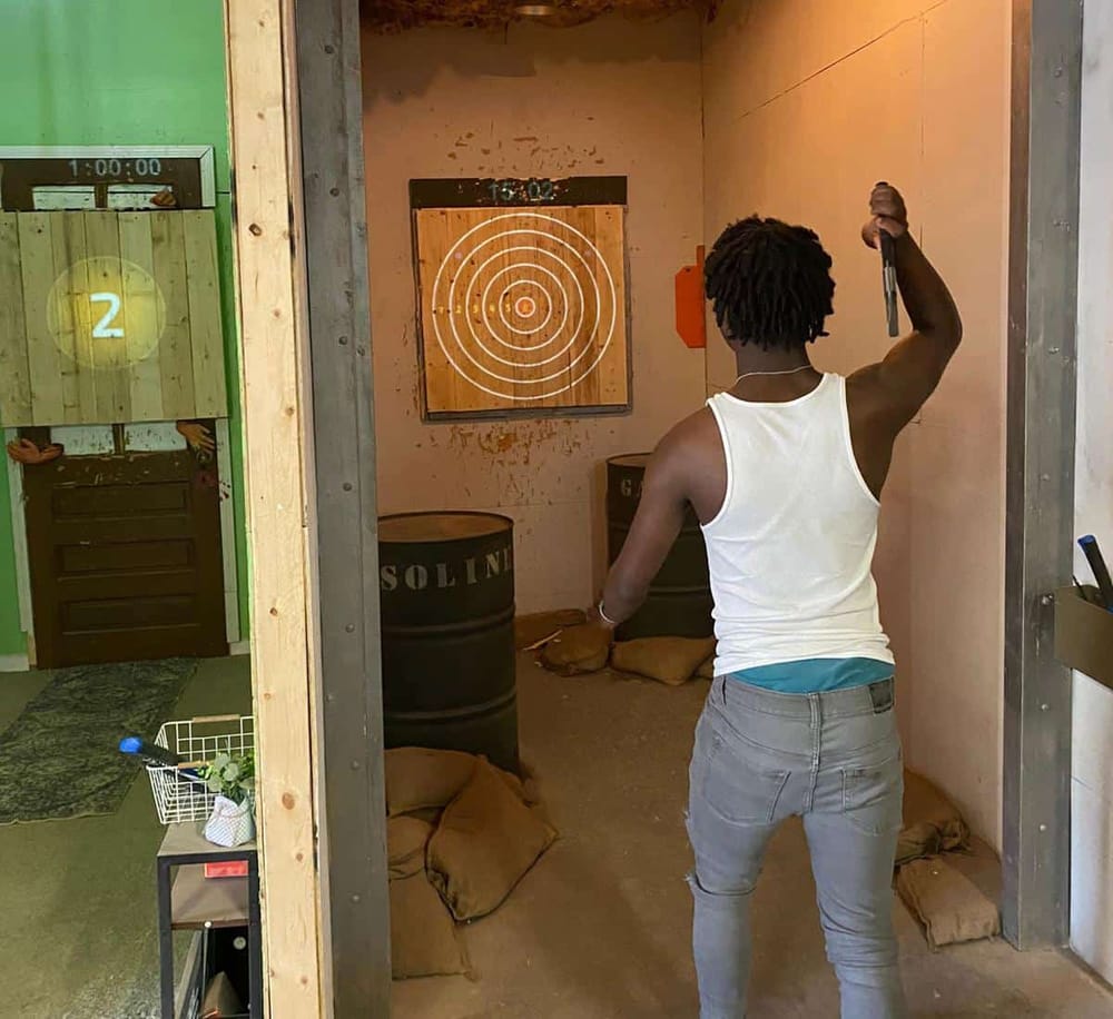 1. Individual playing axe-throwing game in indoor target practice area.