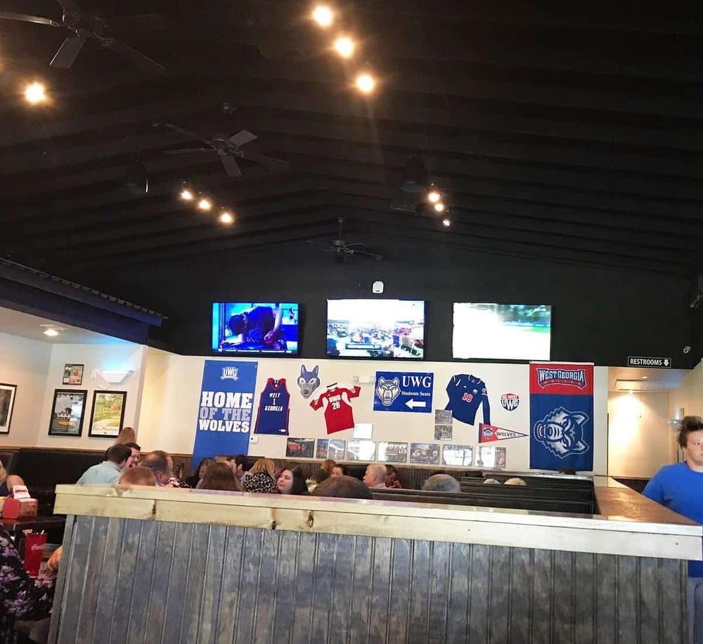 Bright indoor sports bar with multiple TVs, University of West Georgia sports memorabilia, and a lively crowd.
