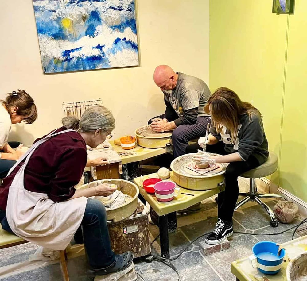 Acrylic pottery class with diverse students using pottery wheels for creative art.