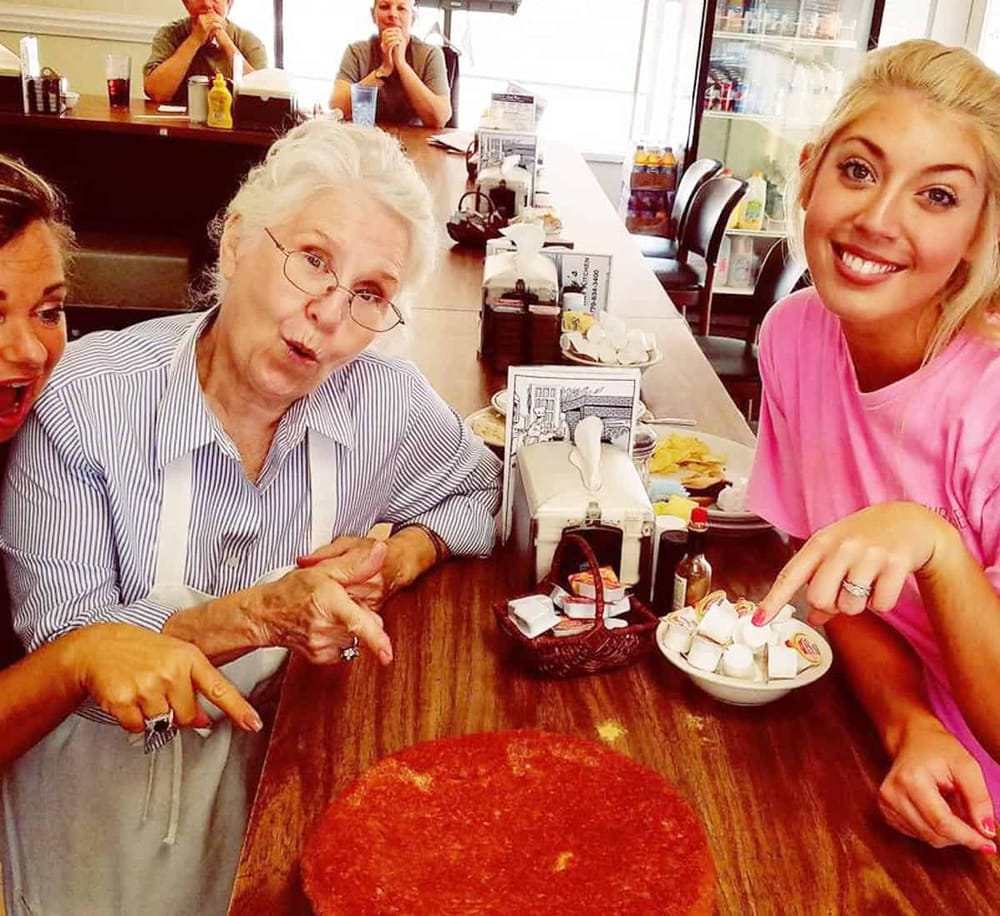 1. Elderly woman and young waitress enjoying a fun moment at a diner.
