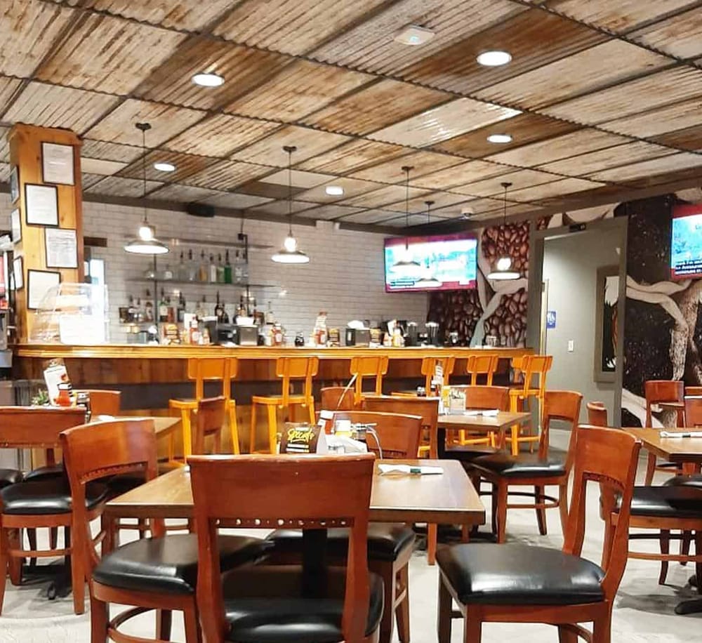 Cozy restaurant interior with wood accents, bar area, and TV screens, perfect for a casual dining experience.