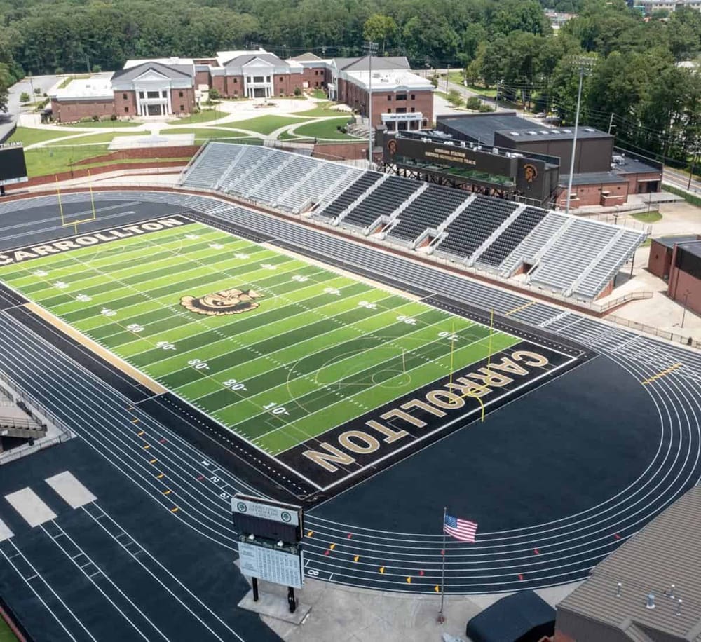 Brighton High School football stadium featuring a state-of-the-art turf, modern bleachers, and surrounding academic buildings.