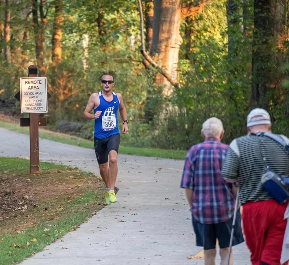 Runners participating in a marathon along a scenic forest trail during outdoor sports event.