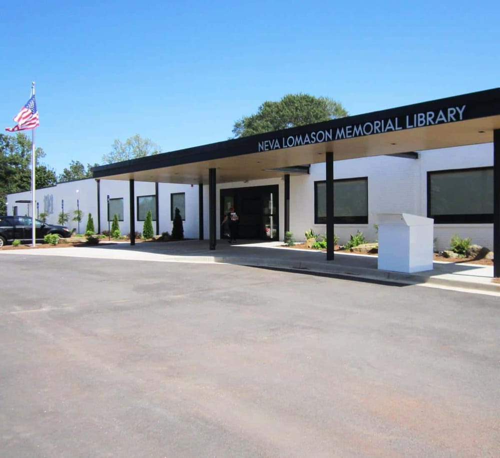 NEVA LOMASON MEMORIAL LIBRARY in a modern, accessible building with landscaped surroundings and American flag.