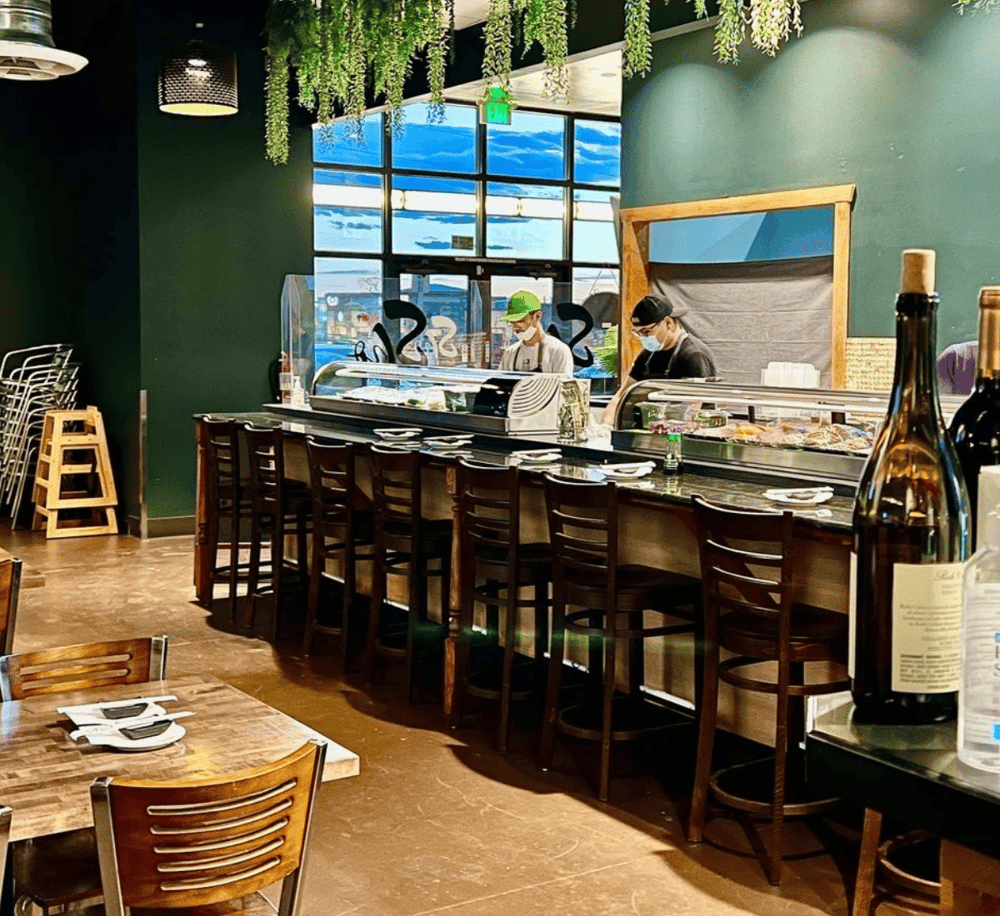 Fresh sushi bar at QuestForDirections restaurant with chefs preparing dishes in a cozy, modern interior.