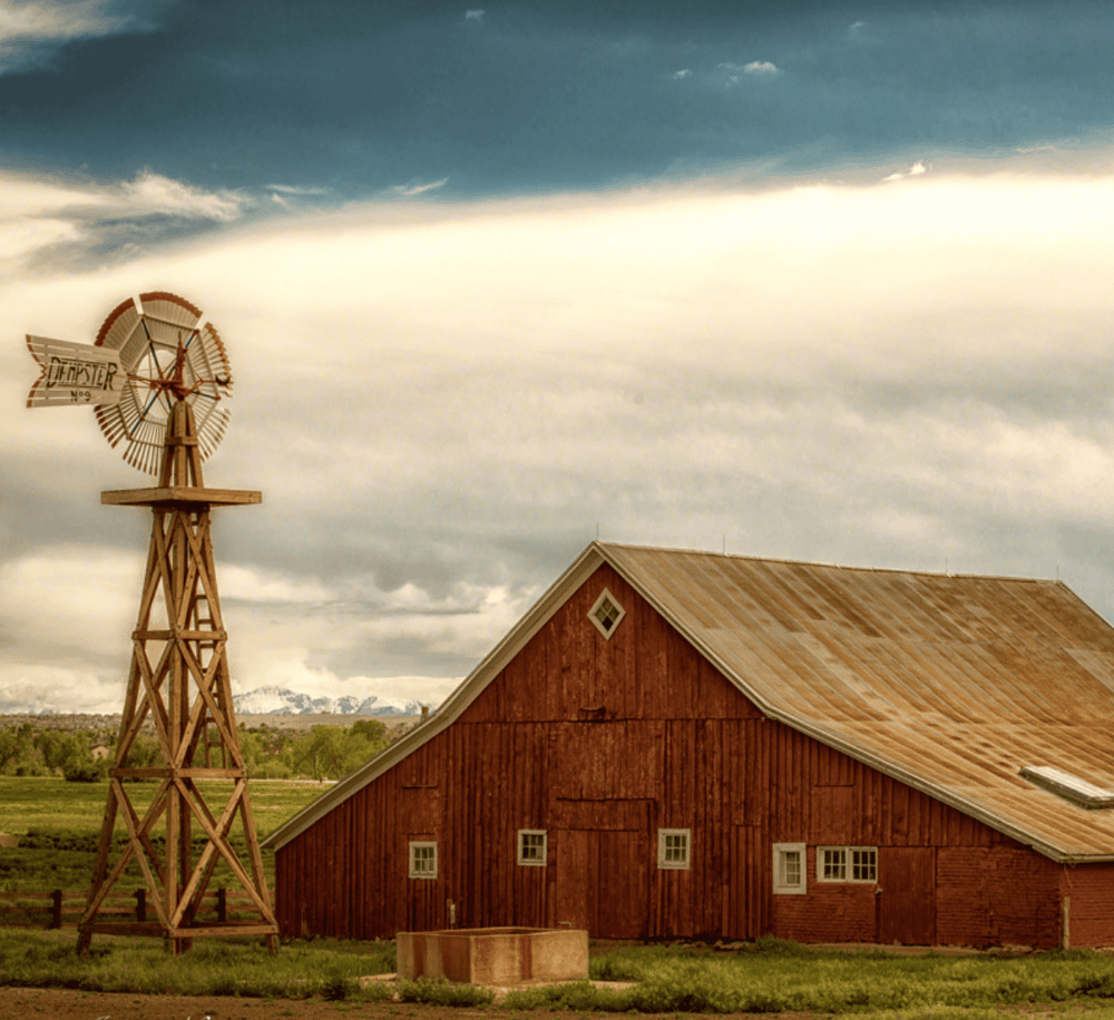 Windmill and rustic barn on a farm, rural landscape with cloudy sky, ideal for guiding directions.