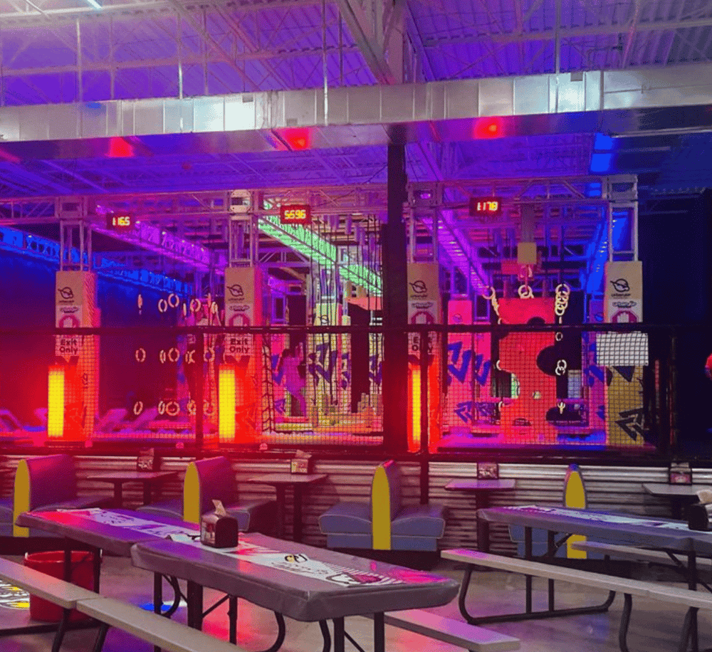 Colorful neon-lit indoor entertainment area with trampoline park and seating.