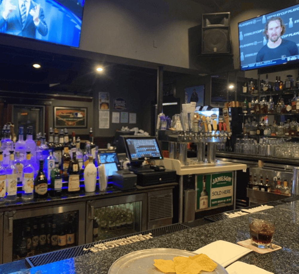 Bright bar with tv screens, liquor bottles, and a shot of drink and snacks, showcasing the vibrant nightlife scene.