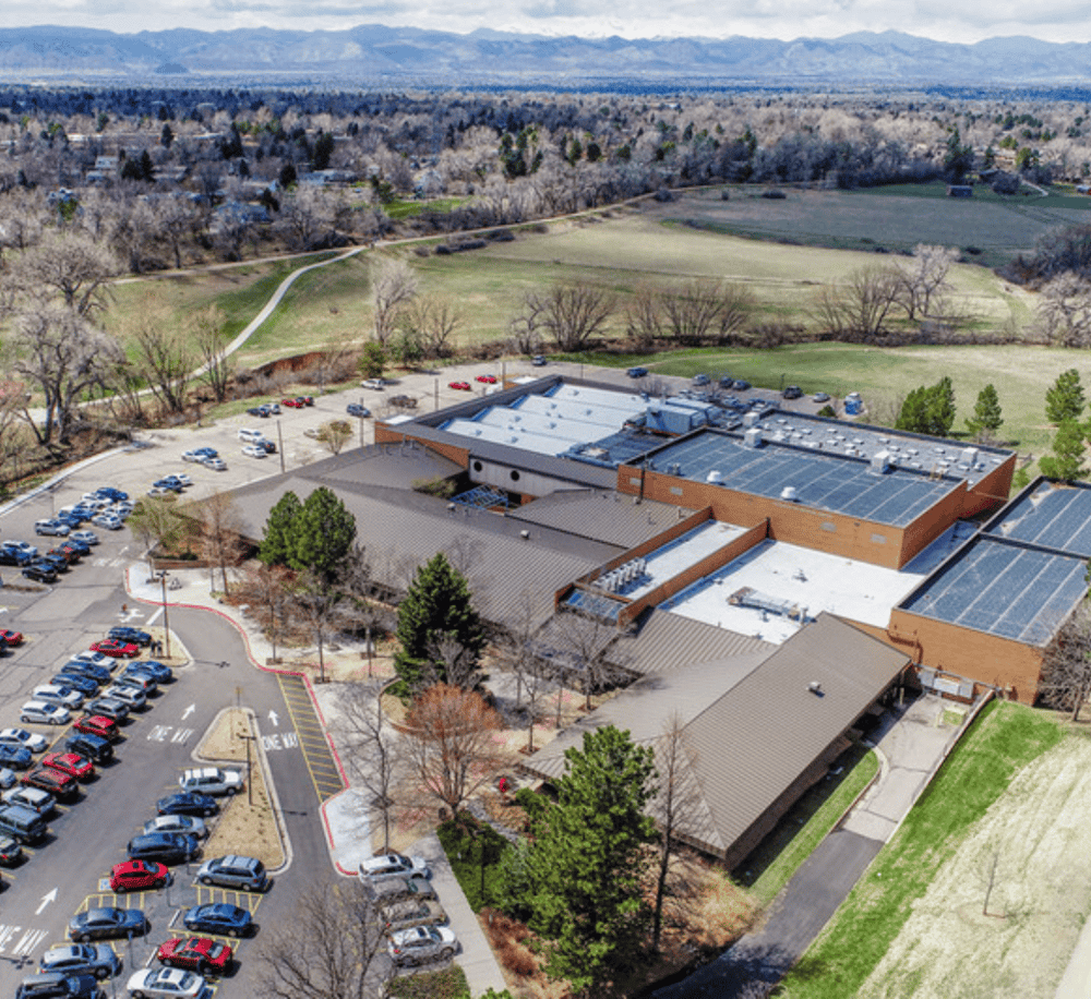 Community center with parking lot and surrounding green space, ideal for local events and outdoor activities.