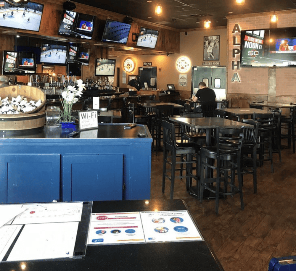 Relaxed sports bar ambiance with multiple TV screens, seating, and a bar area for social dining.