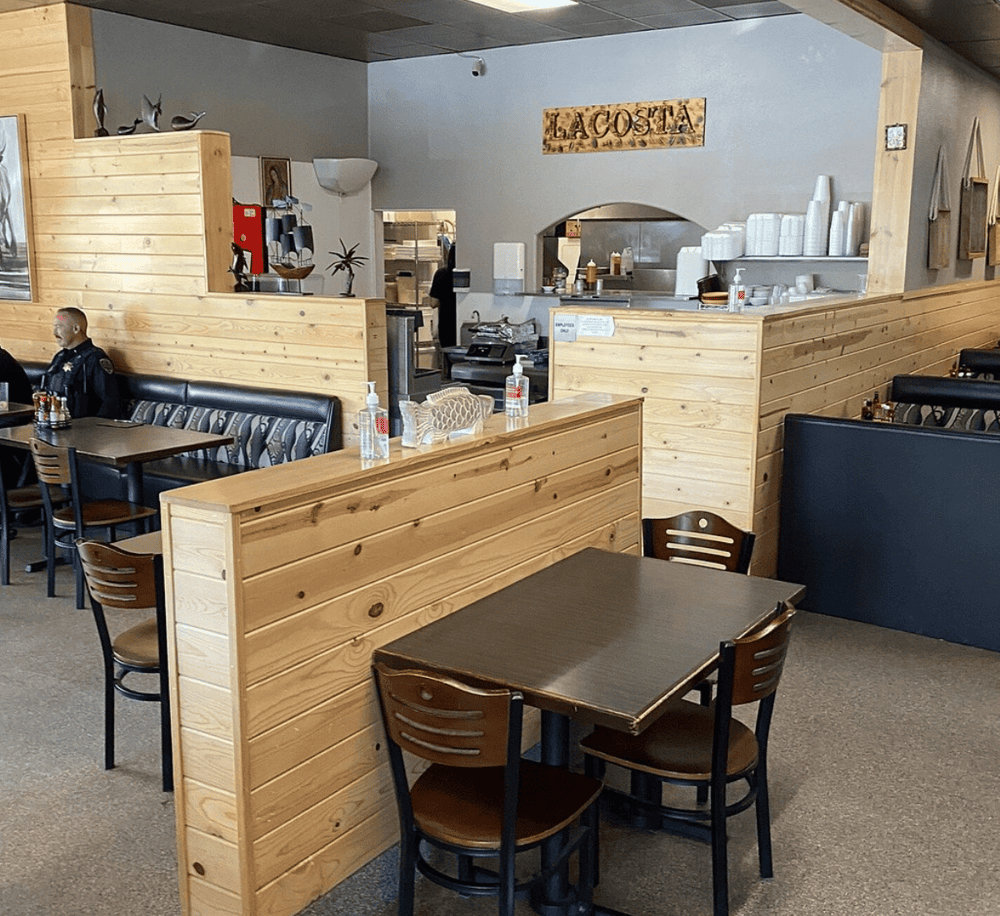 Cozy restaurant interior with wood accents and social distancing measures in place.