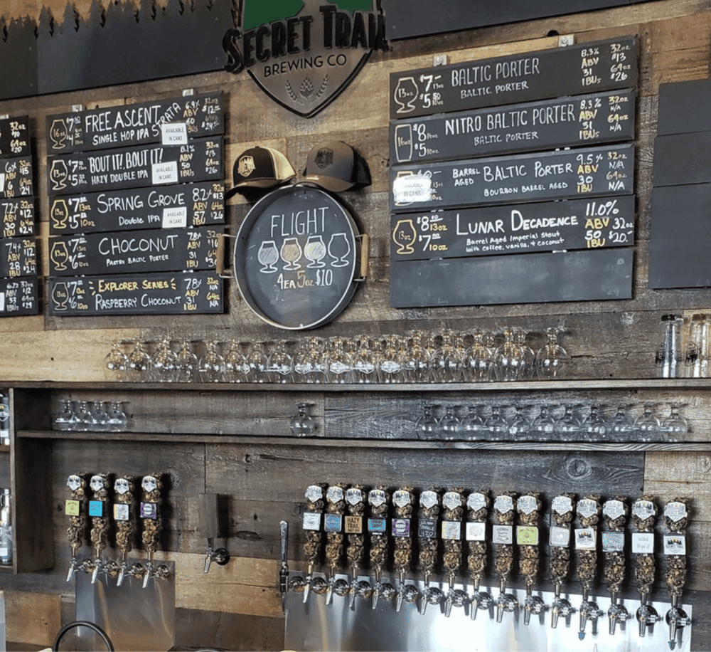 Craft beer taps and menu boards at Secret Trail Brewing Co, offering a variety of Baltic Porters and specialty brews.