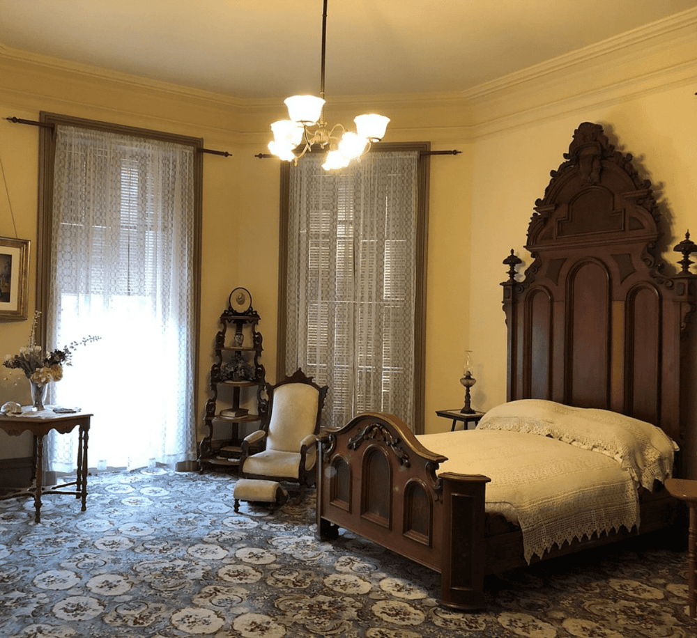 Antique bedroom with vintage furniture and ornate woodwork in a historic home.