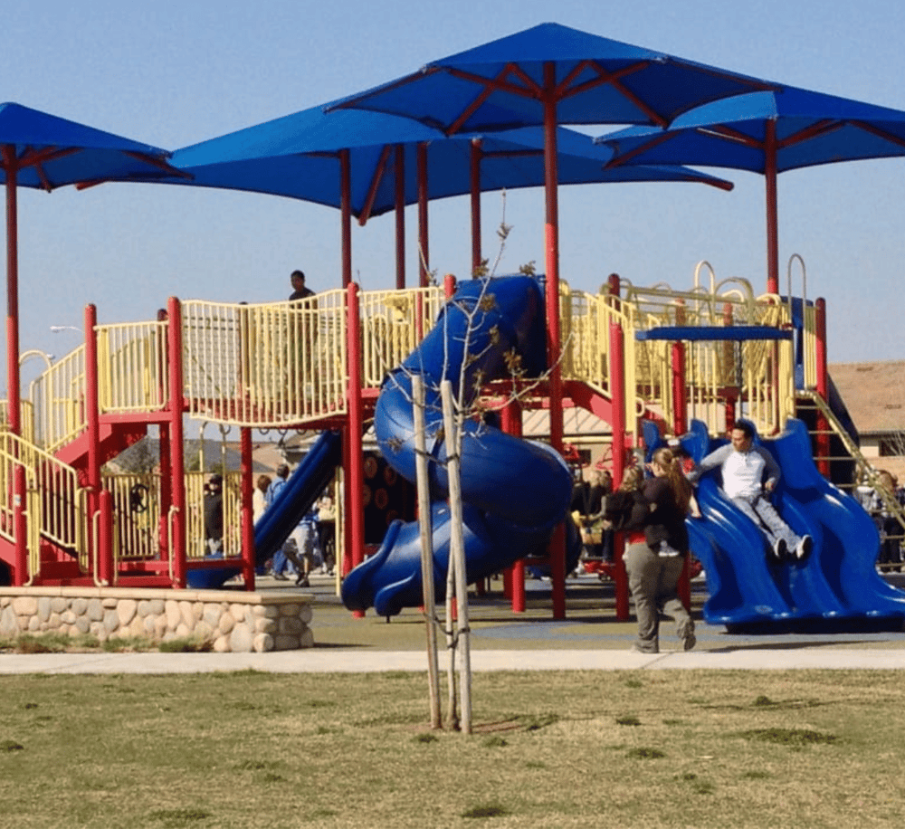 Colorful children's playground with slides and shade canopies, perfect for families and outdoor fun.