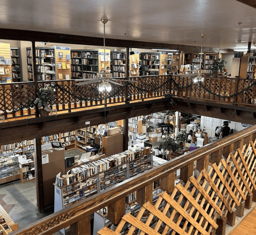 Aisle view of a cozy bookstore with wooden railings and bookshelves filled with books, perfect for book lovers.