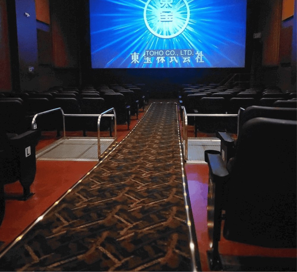 Modern movie theater with accessible ramp and large screen showcasing TOHO Co. branding.