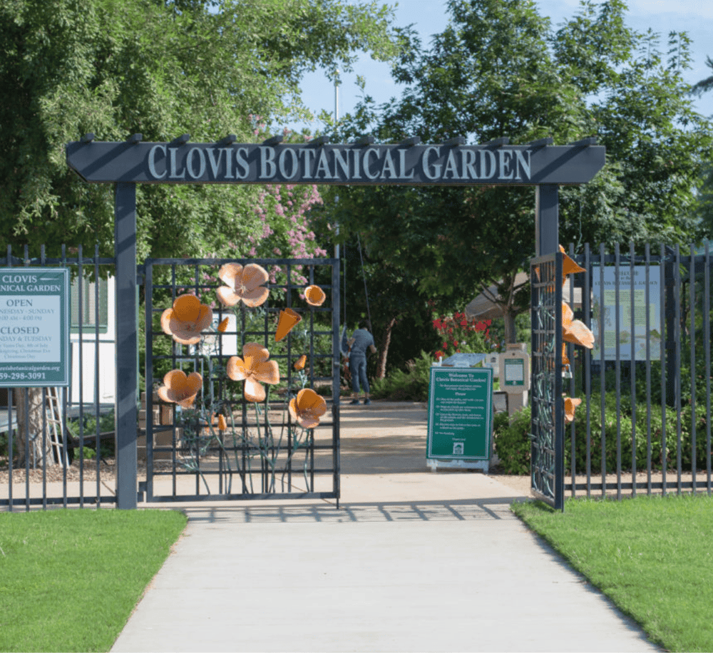Colorful entrance to Clovis Botanical Garden with decorative flowers and lush greenery.