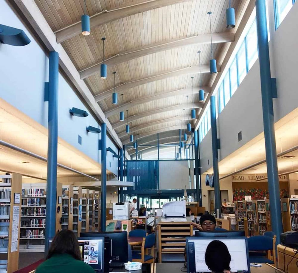 Bright modern library interior with high arched wooden ceiling and blue accents for quiet study.
