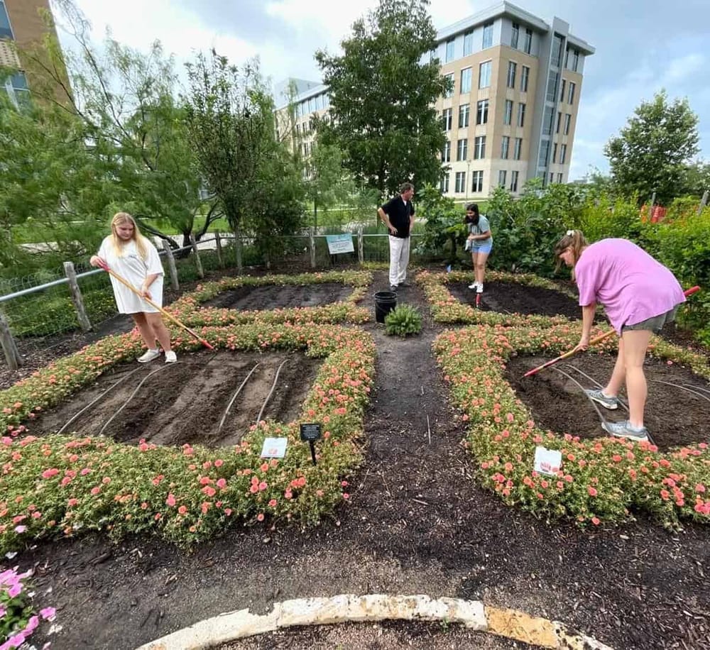 Colorful flower garden with kids planting and gardening activities near modern apartment buildings.