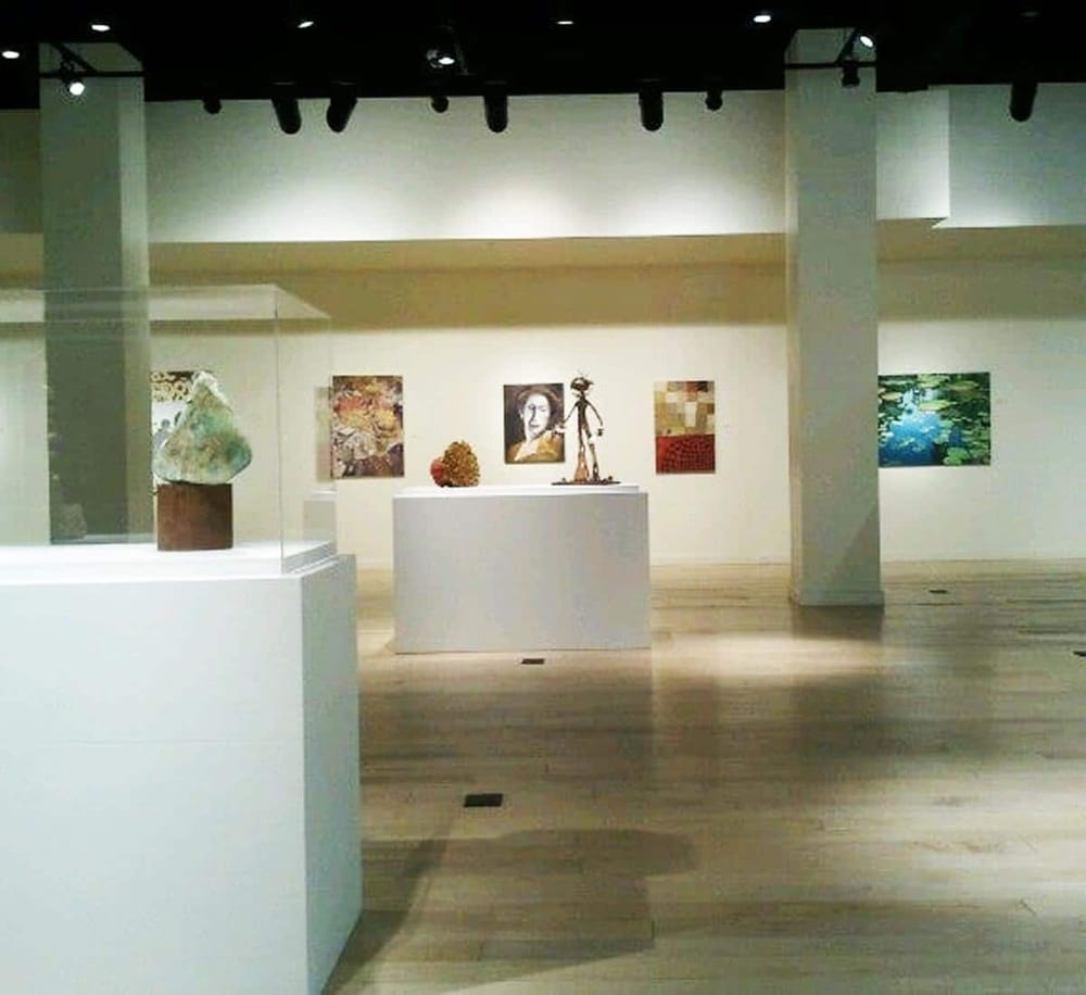 Elegant art gallery showcasing contemporary sculptures and paintings in a spacious, well-lit environment.