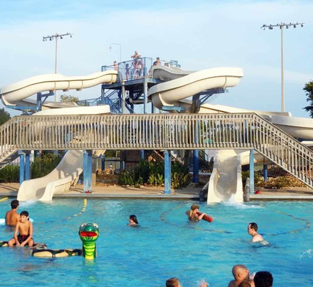 Water park with multiple water slides and swimming area for family fun and recreation.