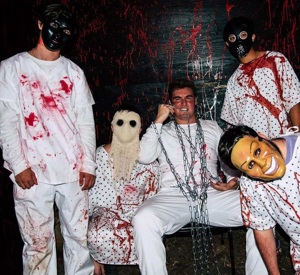 Creepy horror-themed escape room scene with masked individuals, chains, and blood-stained costumes for thrill seekers.