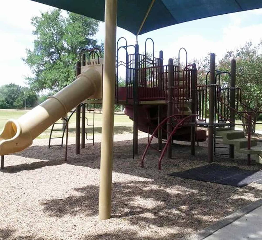 Colorful playground structure with slide and climbing equipment in a park setting.